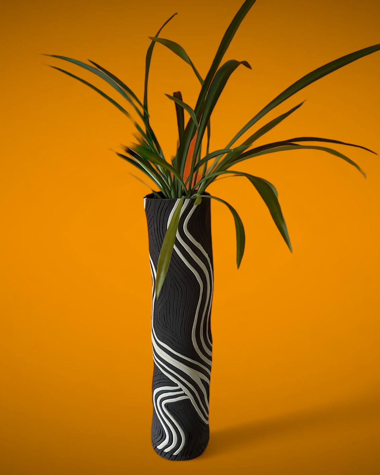 Skulpturale Vase mit Pflanze auf orangem Hintergrund